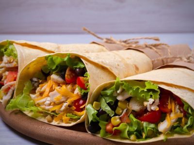 Chicken wraps. Tortilla, burritos, sandwiches twisted rolls on wooden table